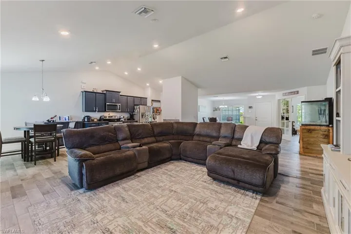 Living area featuring a chandelier, light wood-type flooring, recessed lighting, and high vaulted ceiling