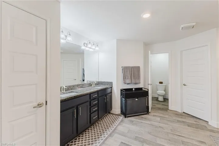 Bathroom with double vanity and light wood-type flooring