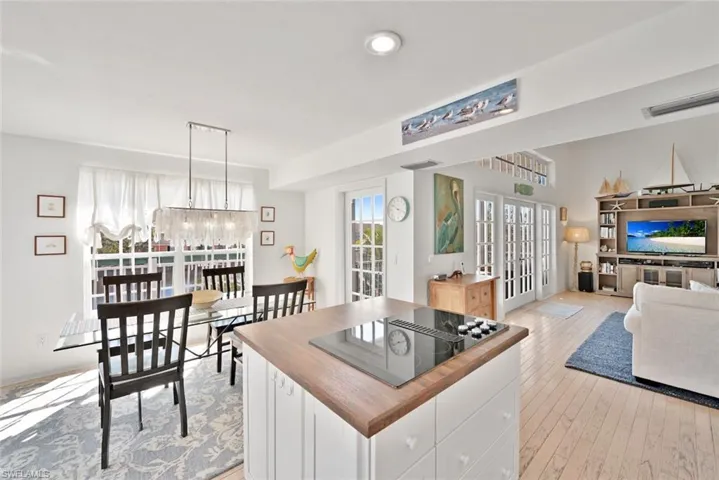 Kitchen with black electric cooktop, decorative light fixtures, a center island, light hardwood / wood-style floors, and white cabinetry
