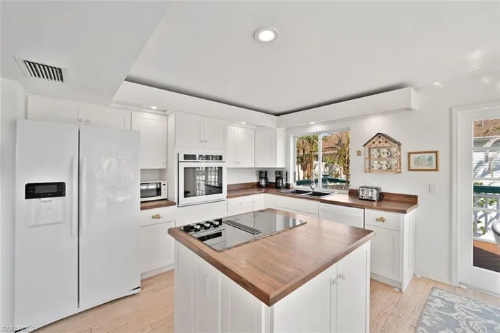Kitchen with white cabinets, light wood-type flooring, and white appliances