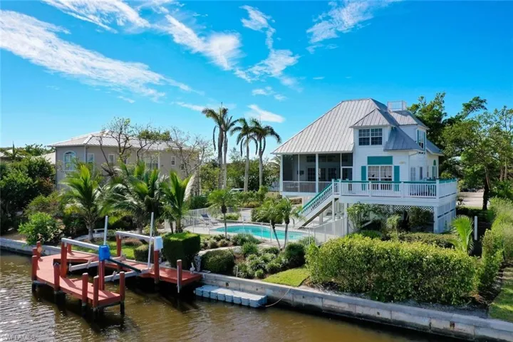 Back of house featuring a sunroom, a swimming pool side deck with water view, and a patio