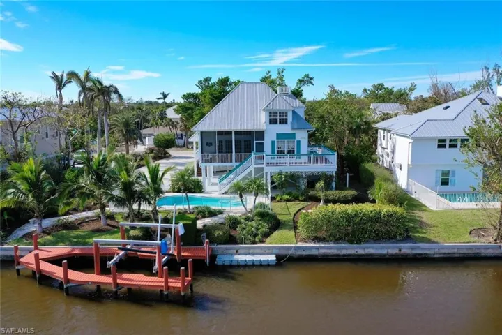 Rear view of house featuring a sunroom, a water view, a yard, and a patio