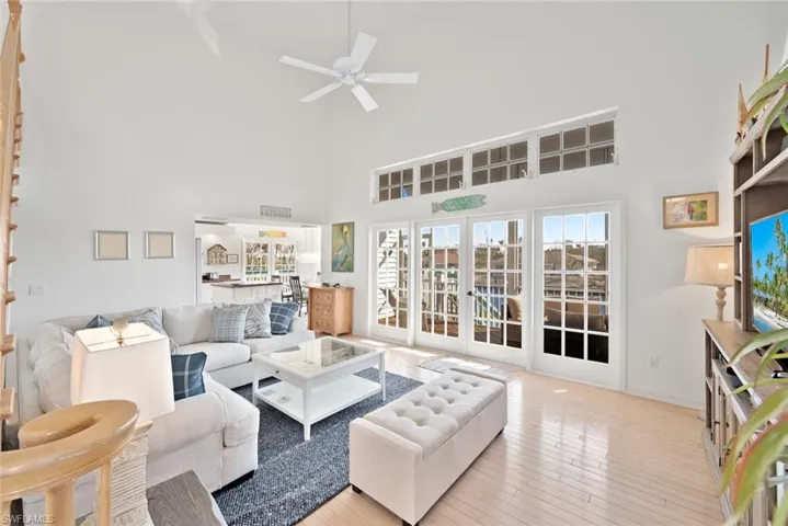 Living room featuring a high ceiling, light wood-type flooring, french doors, and ceiling fan