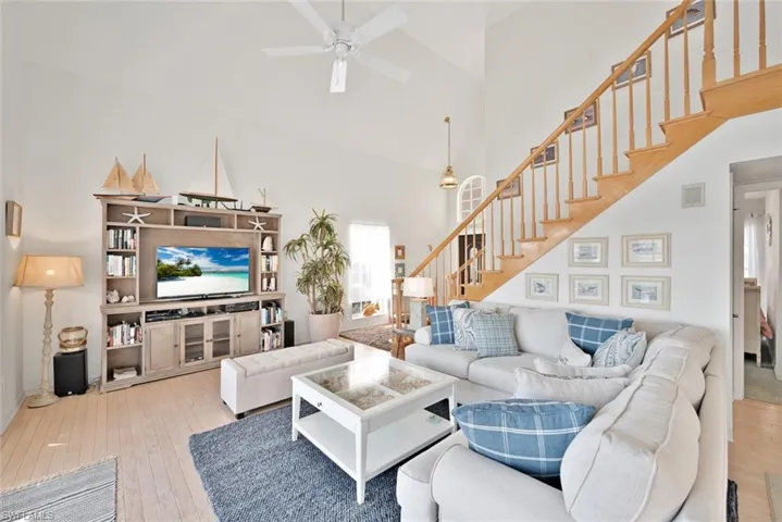Living room with ceiling fan, light hardwood / wood-style floors, and a high ceiling