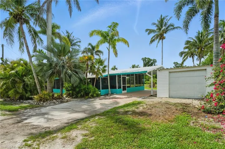 View of front of property with a sunroom, driveway, and an outdoor structure