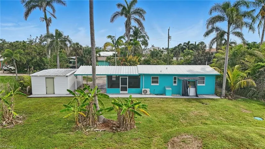 Back of property with a sunroom, a yard, a shed, and a metal roof