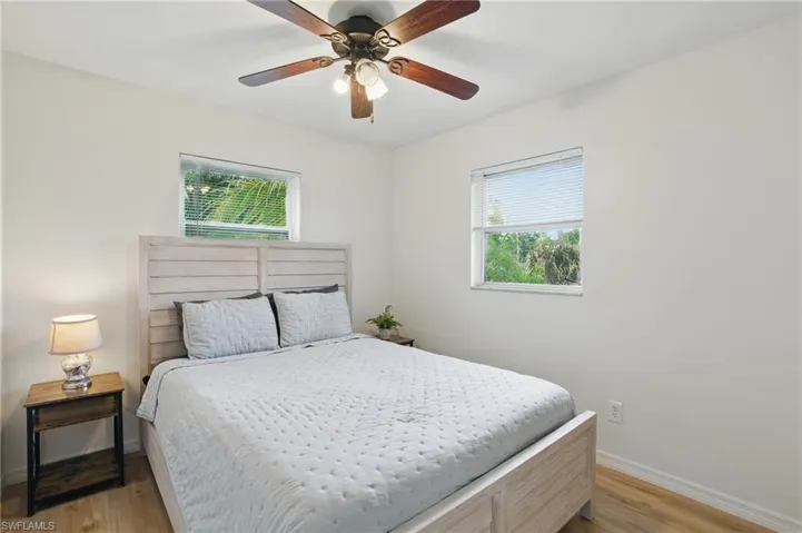Bedroom with multiple windows, light wood-style floors, and ceiling fan