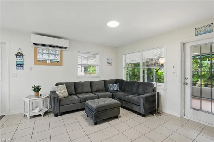 Living area with a wall mounted AC and light tile patterned floors
