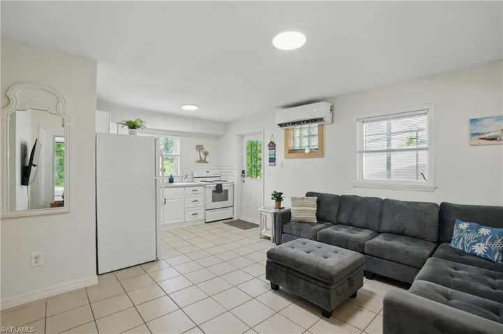Living area with an AC wall unit and light tile patterned floors