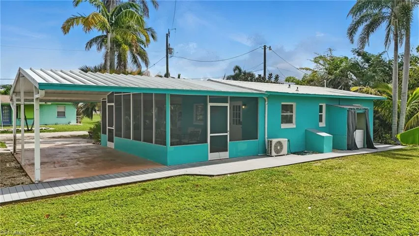 Rear view of property with a sunroom, a yard, and a metal roof