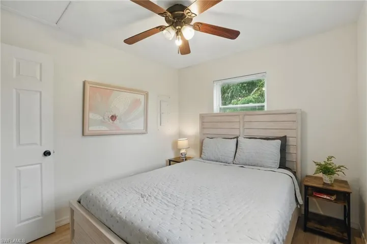 Bedroom featuring light wood-type flooring, a ceiling fan, and attic access