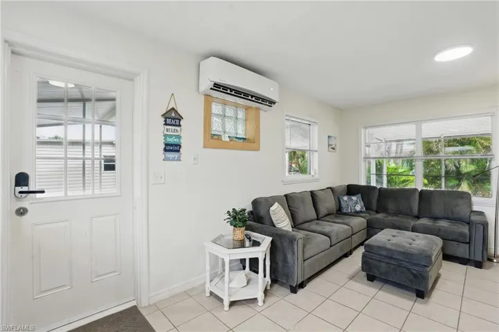 Living room with a wall unit AC and light tile patterned flooring