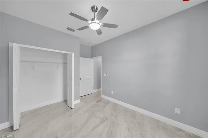 Unfurnished bedroom featuring a closet, baseboards, and a ceiling fan