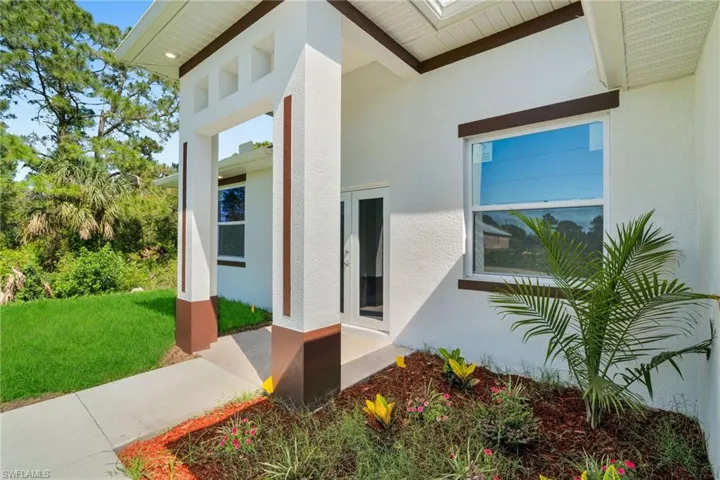 Property entrance featuring stucco siding and a lawn