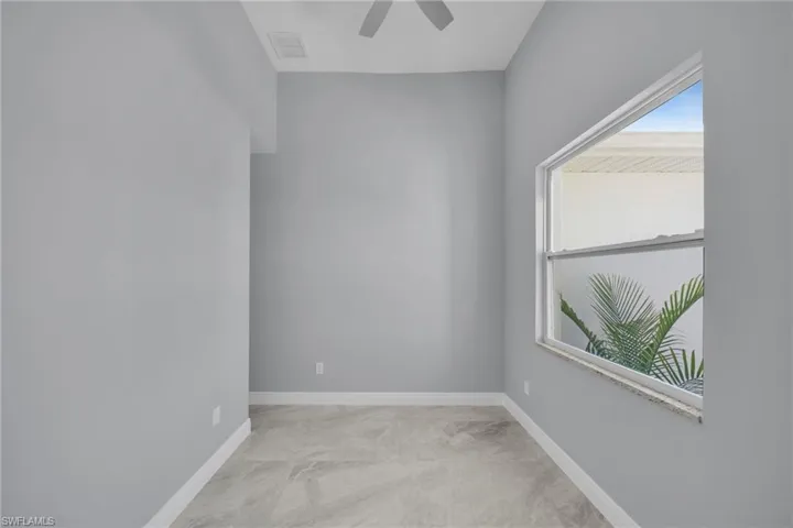 Spare room with a ceiling fan, baseboards, and marble look tile flooring