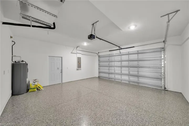 Garage featuring water heater, a garage door opener, electric panel, and recessed lighting
