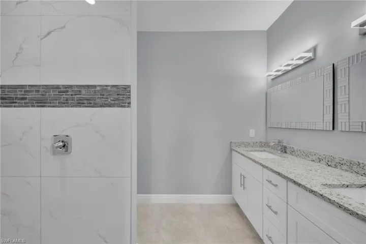 Full bath featuring double vanity and baseboards