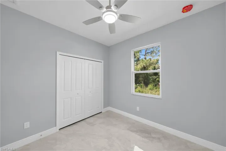 Unfurnished bedroom with baseboards, light marble finish floors, a closet, and a ceiling fan