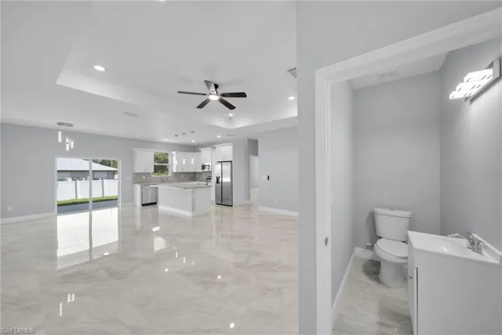 Full bathroom with vanity, marble tiled flooring, toilet, decorative backsplash, and ceiling fan