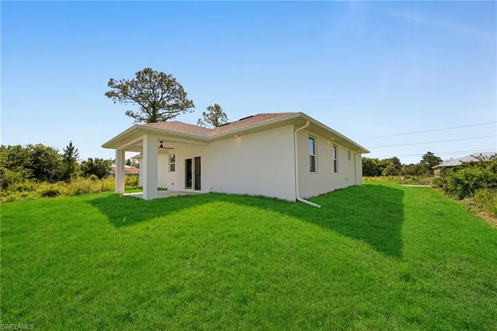 Back of house with a patio area, a yard, and stucco siding