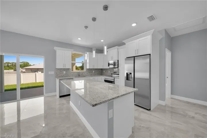 Kitchen with appliances with stainless steel finishes, light marble finish floors, a sink, a center island, and recessed lighting