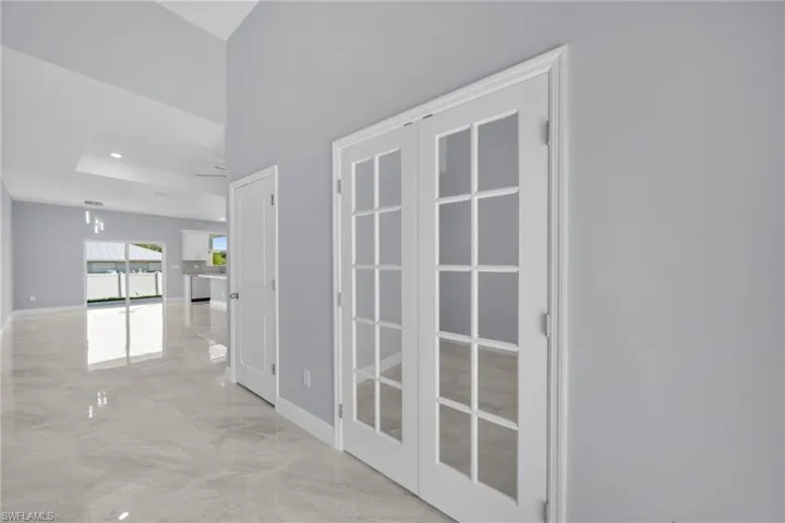 Hall featuring light marble finish floors, baseboards, and french doors