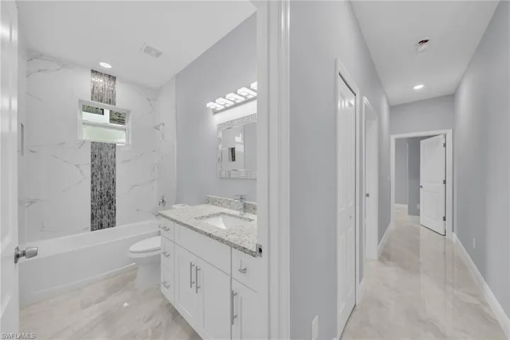 Full bathroom with vanity,  shower combination, toilet, marble finish floors, and recessed lighting