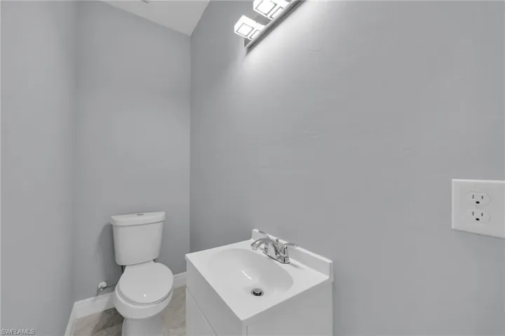 Half bathroom featuring vanity, toilet, and baseboards