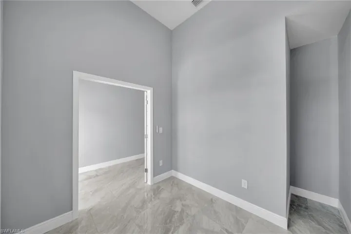 Spare room featuring lofted ceiling and baseboards