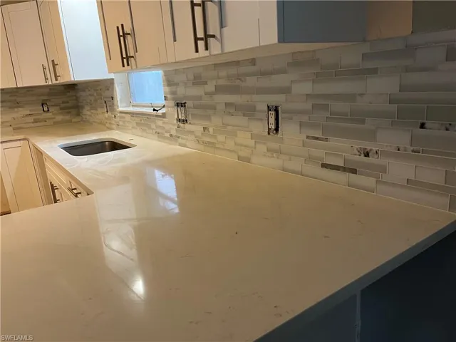 Kitchen featuring white cabinetry, light stone counters, and tasteful backsplash