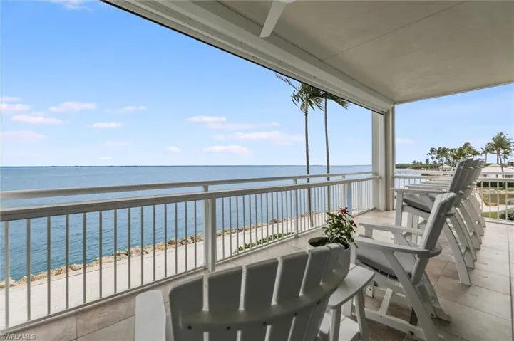 Balcony featuring view of water and beach and a ceiling fan
