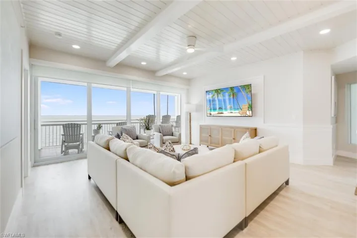 Living area featuring light wood-type flooring, a wood ceiling with exposed beams, a wainscoted wall, ceiling fan, and recessed lighting