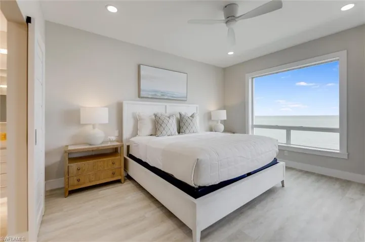 Bedroom with light wood-style floors, a ceiling fan, recessed lighting, and a water view
