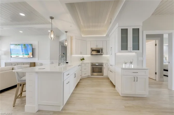 Kitchen featuring a wooden ceiling with exposed beams, a peninsula, open floor plan, white cabinets, and pendant lighting