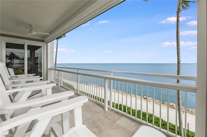 Balcony featuring a ceiling fan and view of water and beach