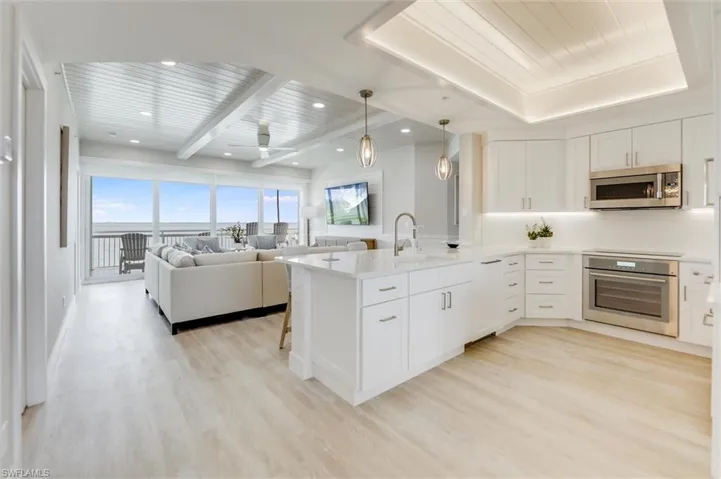 Kitchen with white cabinetry, hanging light fixtures, stainless steel appliances, a breakfast bar, and open floor plan