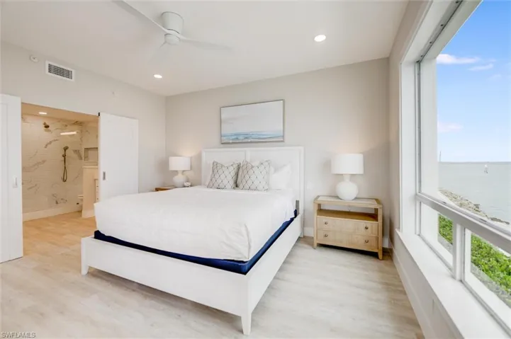 Bedroom with light wood finished floors, ensuite bathroom, multiple windows, a ceiling fan, and recessed lighting