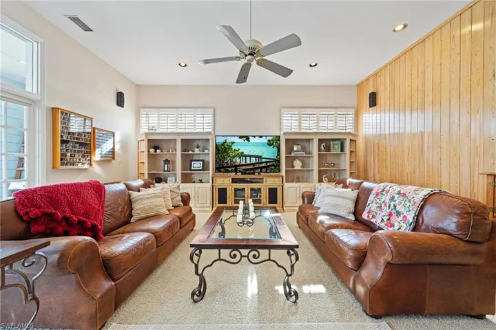 Living area featuring, surround sound, wooden accent wall, recessed lighting, and ceiling fan