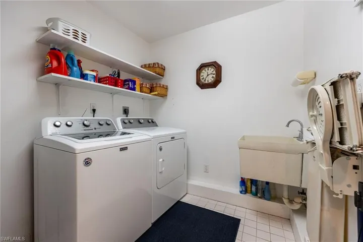 Washroom with a laundry chute, sink and washing machine and clothes dryer