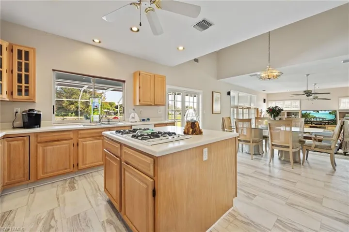 Kitchen featuring ceiling fan, light countertops, a kitchen island, and recessed lighting