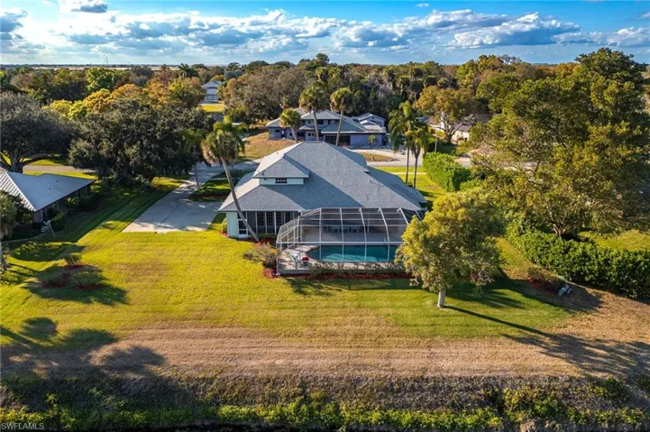 Aerial view of property and surrounding area featuring a tree filled landscape