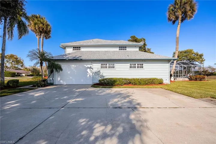 View of side of home with a lawn, oversized driveway, and a garage