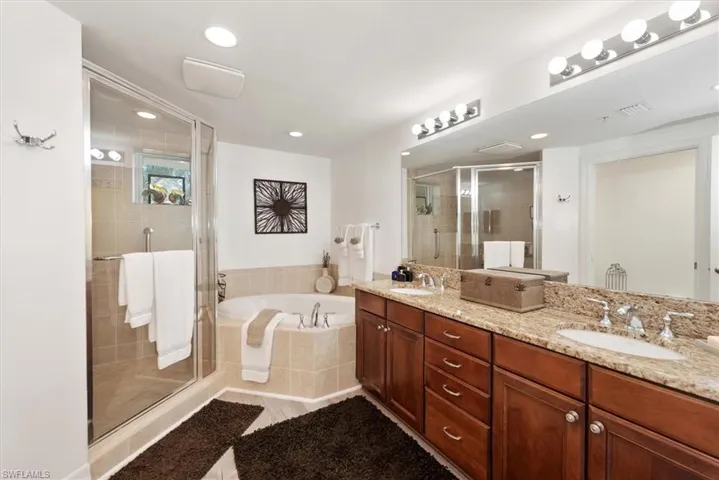 Full bath featuring double vanity, a shower stall, a bath, recessed lighting, and light tile patterned flooring