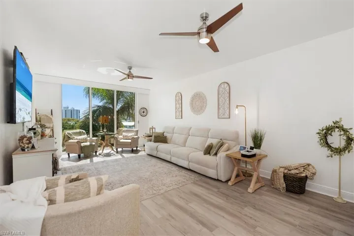 Living room featuring wood finished floors, ceiling fan, and expansive windows