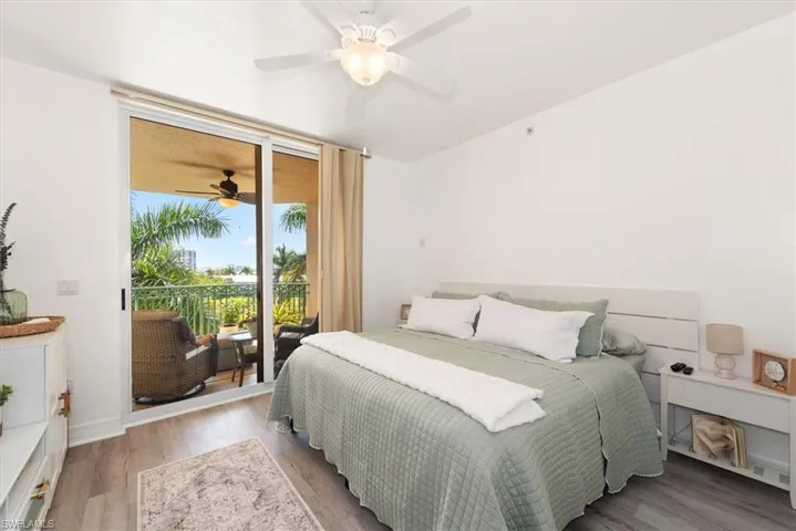 Bedroom with wood finished floors, access to outside, ceiling fan, and expansive windows