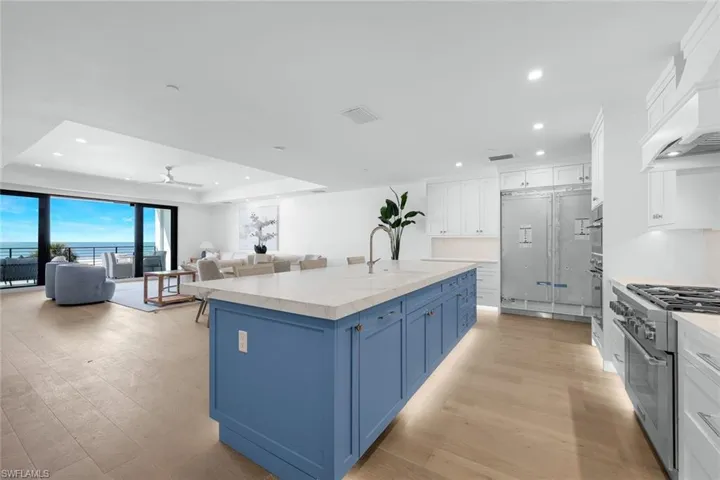 Kitchen featuring two tone color scheme, high end stove, a center island with sink, open floor plan, and recessed lighting
