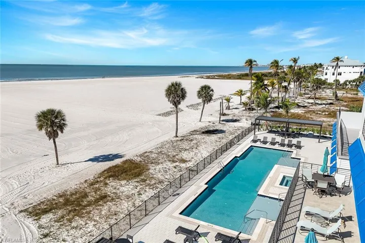Community pool featuring a patio area and view of water and beach
