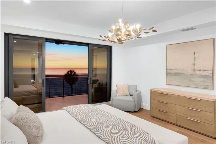 Bedroom featuring light wood-style floors, hanging lights, access to exterior, and a water view