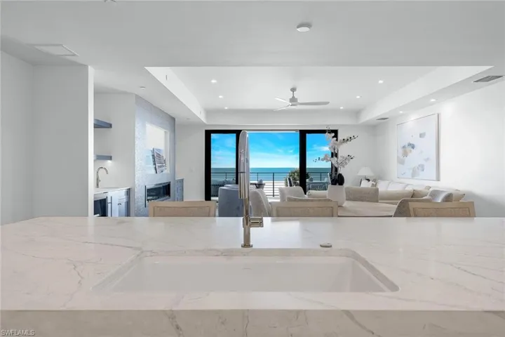Kitchen with light stone countertops, ceiling fan, a tray ceiling, and recessed lighting