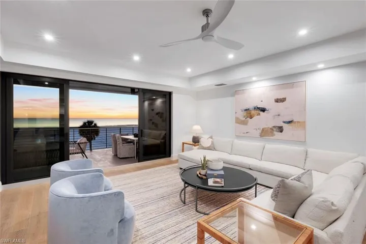 Living room with a water view, light wood-style flooring, ceiling fan, and recessed lighting